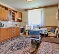 A kitchen in a family house with wooden furniture and a dining area.