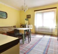 A room in a family house with yellow walls, a table, and a bed.