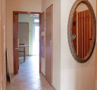 A hallway in a 2-room apartment with a large mirror on the wall and tiles.