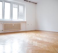 A room in a 2-room apartment with a large window and a floor with a wooden decor.