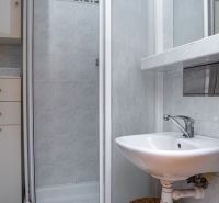 Bathroom in a 2-room apartment with a shower and a sink.