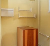 A room in a 2-room apartment with a chandelier, shelves, and tiles.