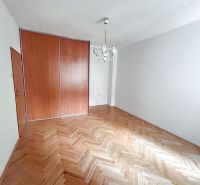 A room in a 2-room apartment with a wooden decor floor and a built-in wardrobe.