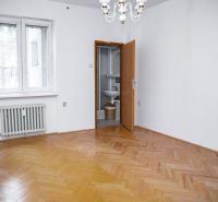 A room with a wooden floor decor, white walls, and a radiator in a 2-room apartment.