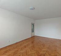 An empty room with a wooden floor and white walls in a two-room apartment.