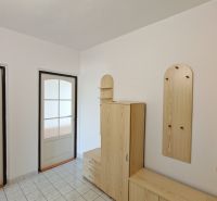 Hallway of a 2-room apartment with wooden storage furniture and glass doors.