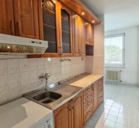 A kitchen unit with wood decor and a stove in a 2-room apartment.