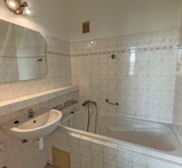 Bathroom in a 2-room apartment with a bathtub, sink, and white tiles.