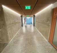 A hallway with concrete walls and a terrazzo floor in a 2-room apartment.