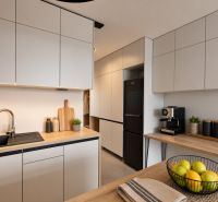 A kitchen with a wooden decor floor in a 2-room apartment, light furniture sets, and appliances.