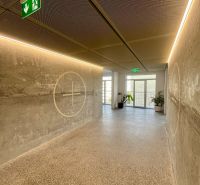 A corridor in an apartment building with concrete walls and emergency exit signs.