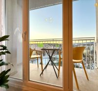 A balcony with a tea table and two yellow chairs in a 2-room apartment.