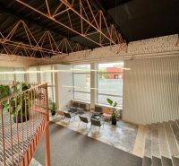 A large interior with metal ceiling structures, a staircase, and seating in a studio apartment.