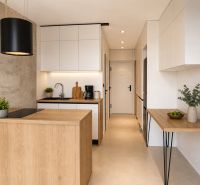 A kitchen in a 2-room apartment with a light-colored kitchen unit and a floor with a wooden decor.