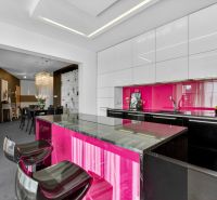 The kitchen of a 4-room apartment with a bright pink cabinet and stylish chairs.