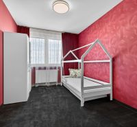 A children's room with red walls, white furniture, and a window in a 4-room apartment.