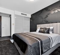 Bedroom in a 4-room apartment with patterned black wallpaper and a comfortable bed.