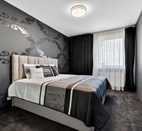 A bedroom with patterned wallpaper, a large bed, and dark curtains in a 4-room apartment.