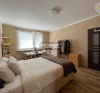 A bedroom in a 3-room apartment with a bed, a desk, and a wooden decor floor.
