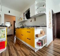 A kitchen with yellow cabinets and a wood-patterned floor in a 3-room apartment.