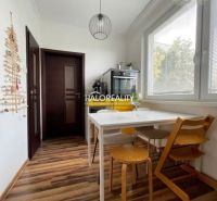 A kitchen in a 3-room apartment with a white table and a wooden decor floor.