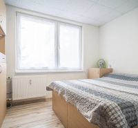 Bedroom in a 2-room apartment with wardrobes and a bed, floor with wood decor.