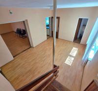 Interior of a family house with a staircase and wood-patterned flooring, open space.