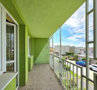 The balcony of a family house on Lesná Street in Čaňa with a green facade and a view of the street.