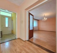 A room in a family house with a wooden decor floor and a chandelier.