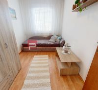 A room in a 3-room apartment with a wooden decor floor, sofa, wardrobe, table.