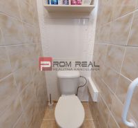 A toilet with beige tiles in a 3-room apartment.