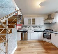 A kitchen in a family house with white cabinets, a stainless steel dishwasher, and a wooden-patterned floor.