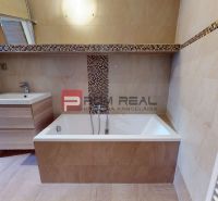 A bathroom in a family house with a bathtub, sink, and designer tiles.