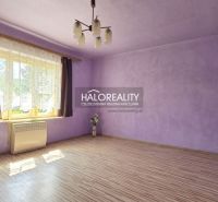A room with purple walls, a light fixture, a wooden-patterned floor, and a window with dark curtains.