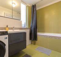 A bathroom in a 2-room apartment with a bathtub, washing machine, and mirrored cabinet.