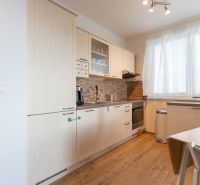 A bright kitchen with a kitchen unit and a wooden decor floor in a 2-room apartment.