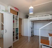 A room with a bunk bed, cabinets, and a wooden decor floor in a two-room apartment.