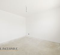 An empty room in a family house with white walls and an unfinished floor.
