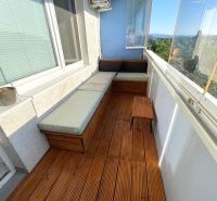 Balcony of a 2-room apartment with seating and flooring with a wooden decor.