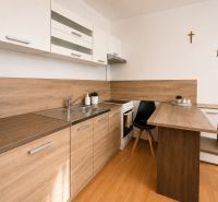 Kitchen unit in a studio apartment with a wooden decor floor and a dining table.