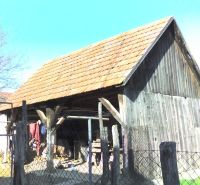 A wooden shed next to a family house in Nové Sady with a red tile roof.