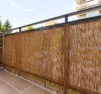 Balcony of a 3-room apartment with rattan screening, ceramic flooring, view of the surroundings.