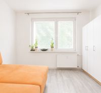 A room in a 3-room apartment with an orange sofa and a white wardrobe.