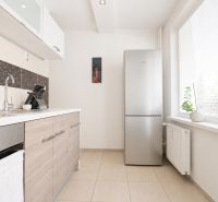 A kitchen in a 3-room apartment with tiles and a refrigerator, bright lighting.