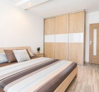 Bedroom with a double bed, wardrobe, and wooden decor flooring in a 3-room apartment.