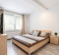 A bright bedroom with a bed and a wooden decor floor in a 3-room apartment.