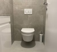 Bathroom with toilet and simple white tiles in the office.
