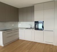 A kitchen with a corner unit, built-in oven, and a floor with wood decor in offices.