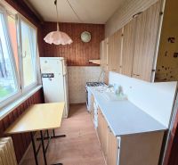 A kitchen in a 3-room apartment with wooden paneling and a floor with a wooden decor.