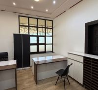 Offices with wood-patterned flooring, simple interior, white walls, black chairs.
